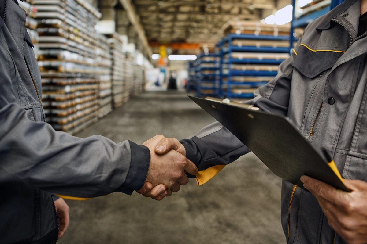 Two workers shaking hands in a factory