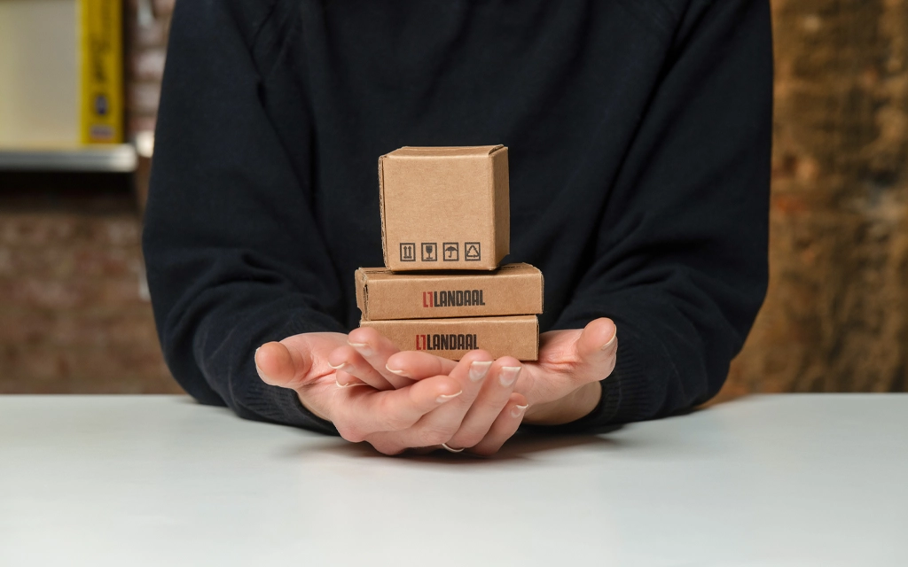 Hands holding miniature Landaal boxes